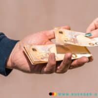 Bürgergeld Auszahlung: Dauer, Tipps & Tricks für eine schnelle Bewilligung 4 Hand hält 50 Euro Scheine, andere Hand gibt einen 50 Euro Schein hinzu