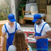 Umzug bei Bürgergeld / Grundsicherung: Jobcenter-Richtlinien 2026, Kosten, Antrag, Urteil! Das sollten Sie wissen! 4 Zwei Mitarbeiter stehen vor LKW mit Möbeln, Mann und Frau sehen zu