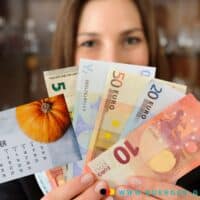 Auszahlungstermine Tabelle Oktober 2024 - Bürger & Geld 4 Frau hält Euro-Scheine in der Hand und einen Kalender mit dem Blatt für Oktober