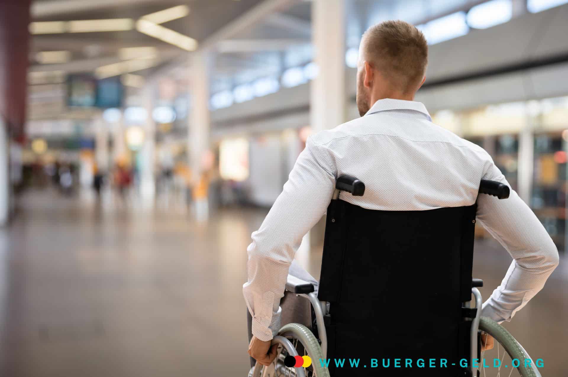 buergergeld und erwerbsminderungsrente gleichzeitig beziehen Mann sitzt im Rollstuhl und fährt durch Gebäude