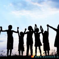Kindergrundsicherung gescheitert – oder kommt sie 2025 doch noch? 4 Kinder halten sich im Gegenlicht der untergehenden Sonne an hochgehobenen Händen und bilden eine Kette