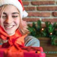 Weihnachtsgeschenke 2024: Deutsche geben Rekordsumme aus - Bürgergeld-Empfänger bleiben außen vor 5 Eine Frau mit Weihnachtsmütze hält ein Geschenk.