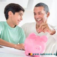 Kindergeld neu im Januar 2025: Auszahlung des erhöhten Betrages 4 Vater und Sohn werfen Münze in Sparschwein