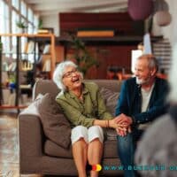 Wer im Februar 2025 in Rente wegen Alters gehen kann – nicht muss 4 Rentner-Ehepaar lacht auf dem Sofa