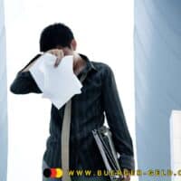 Auszahlung Arbeitslosengeld März 2025 - wann kommt das Geld? 5 Mann hält sich Papier vor das Gesicht