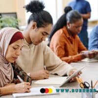 Der Migranten-Anteil beim Bürgergeld – Ist er zu hoch? 4 Menschen mit Migrationshintergrund schreiben an einem Tisch