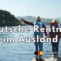 Traumziel Auslandsruhestand: Wo deutsche Rentner ihren Lebensabend verbringen 4 Ein älteres Paar mit Rucksäcken steht am Ufer eines Sees und blickt auf das Wasser und die bewaldete Landschaft; beide heben fröhlich eine Hand in die Luft, als Ausdruck von Freiheit und Aufbruchsstimmung. Im Vordergrund steht der Schriftzug „Deutsche Rentner im Ausland“.
