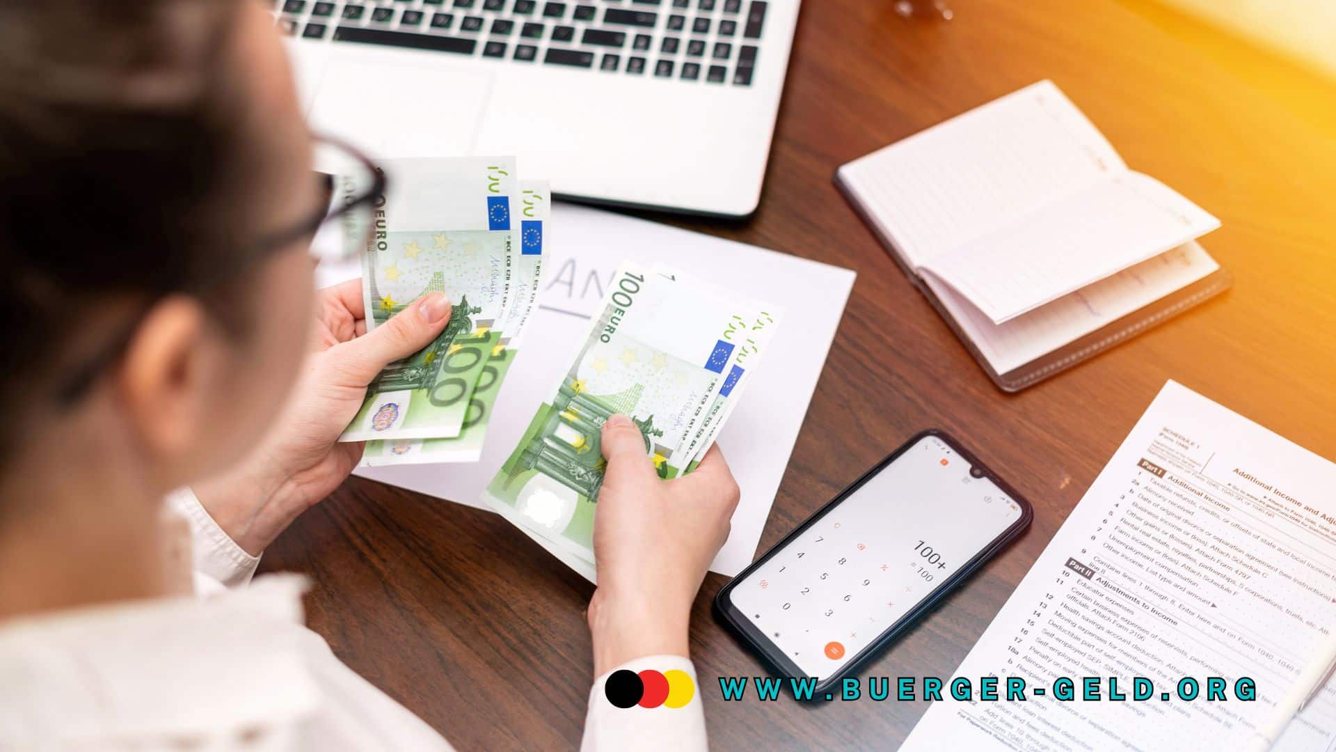 Frau zählt 100-Euro-Scheine am Schreibtisch, vor ihr liegen Laptop, Smartphone mit Taschenrechner, offene Notizbücher und Steuerunterlagen. Auf dem Bild ist die URL www.buerger-geld.org sichtbar.