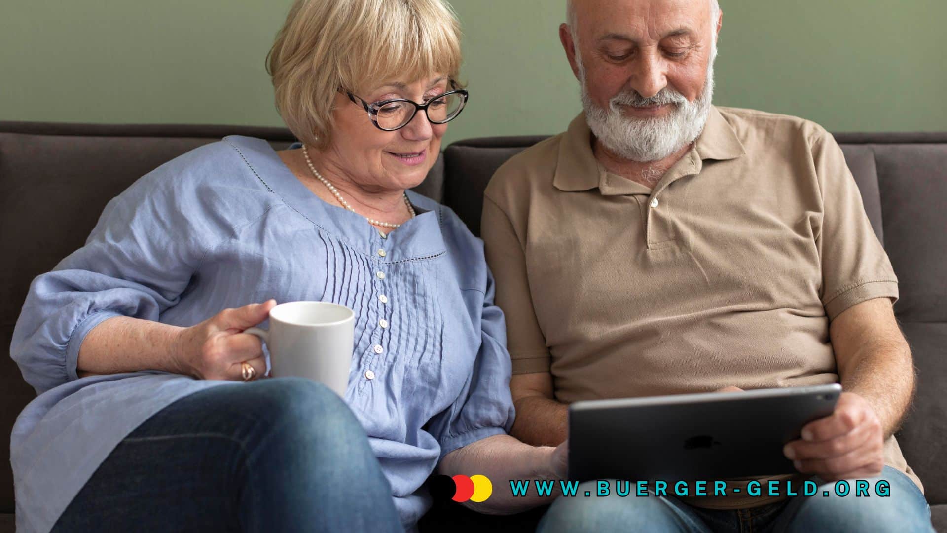 Seniorenpaar sitzt gemeinsam auf dem Sofa, schaut entspannt auf ein Tablet und trinkt Kaffee; eingeblendete Webadresse www.buerger-geld.org.