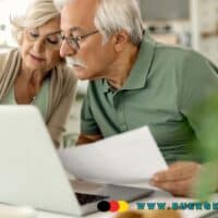 Wie hoch ist meine Rente nach 45 Jahren? 4 älteres Ehepaar analysiert Werte am Notebook