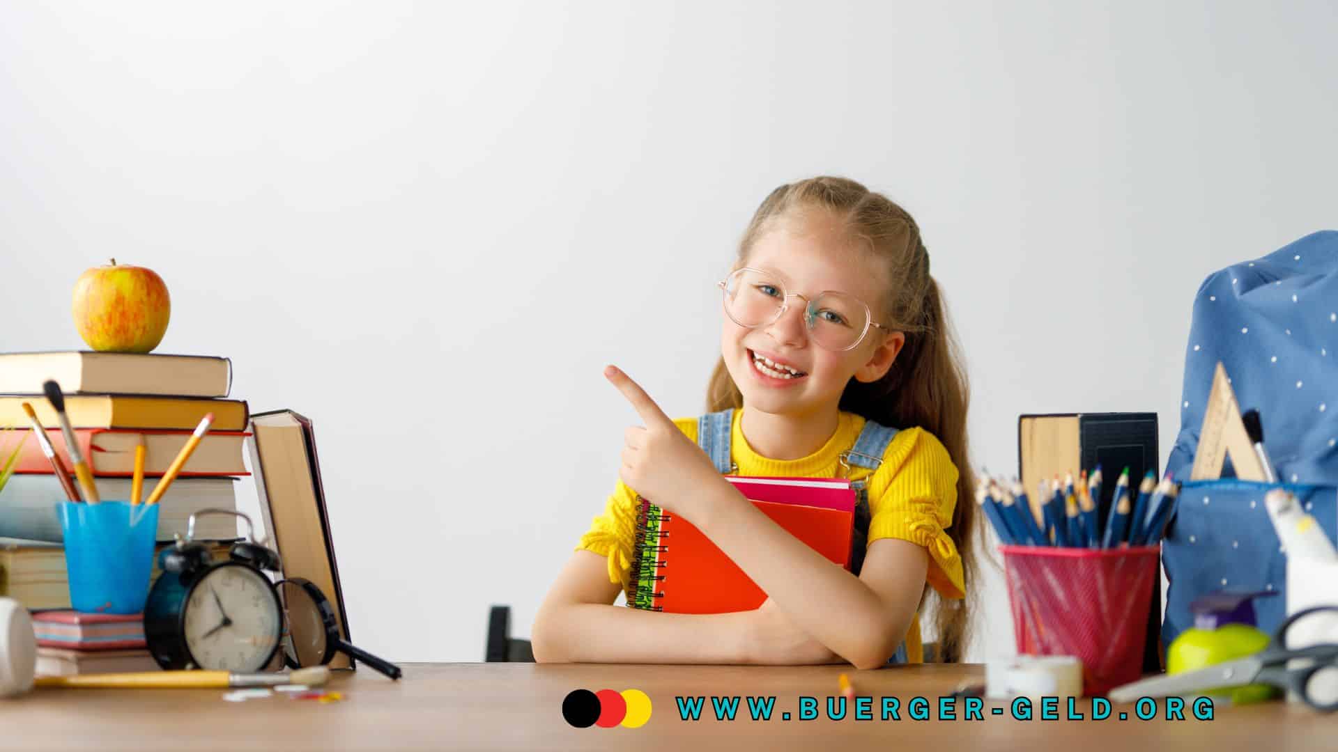 Mädchen mit Zöpfen im gelben Shirt sitzt an einem Schreibtisch, hält ein rotes Notizbuch im Arm und zeigt mit dem Finger nach links; auf dem Tisch liegen Bücher, eine Schuluhr, ein Apfel, Stifte sowie eine blaue Schultasche.