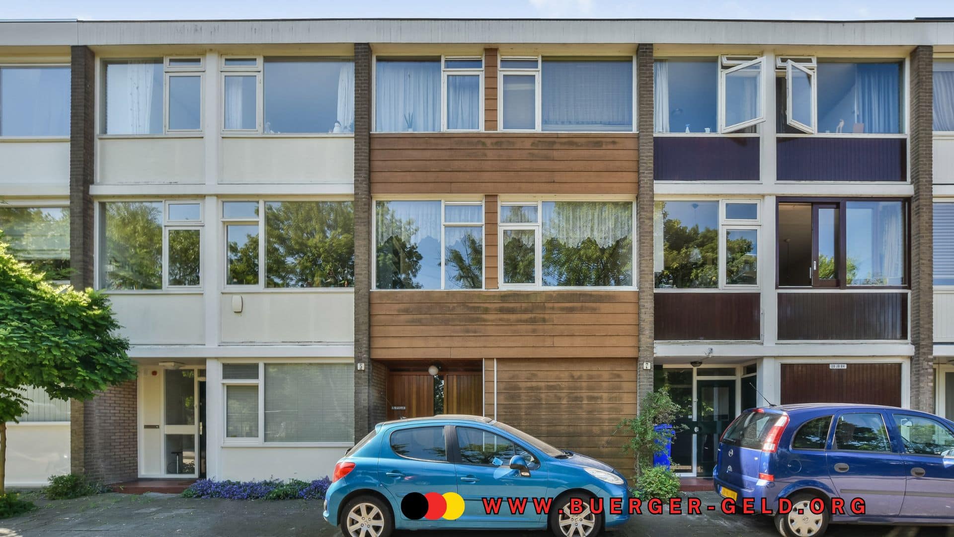 Dreistöckiges Mehrfamilienhaus mit mehreren Wohnungen, davor zwei geparkte Autos und ein Baum, auf dem vorderen Auto sowie im Bild unten das Logo und die Webadresse von buerger-geld.org.