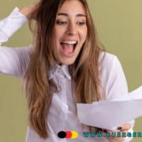 Schulden loswerden: Die besten Wege zur finanziellen Unabhängigkeit 4 Frau mit langen braunen Haaren steht vor einem hellgrünen Hintergrund, trägt ein weißes Hemd und hält mehrere Dokumente in der Hand. Sie wirkt nachdenklich und leicht gestresst, während sie sich mit einer Hand an den Kopf fasst.