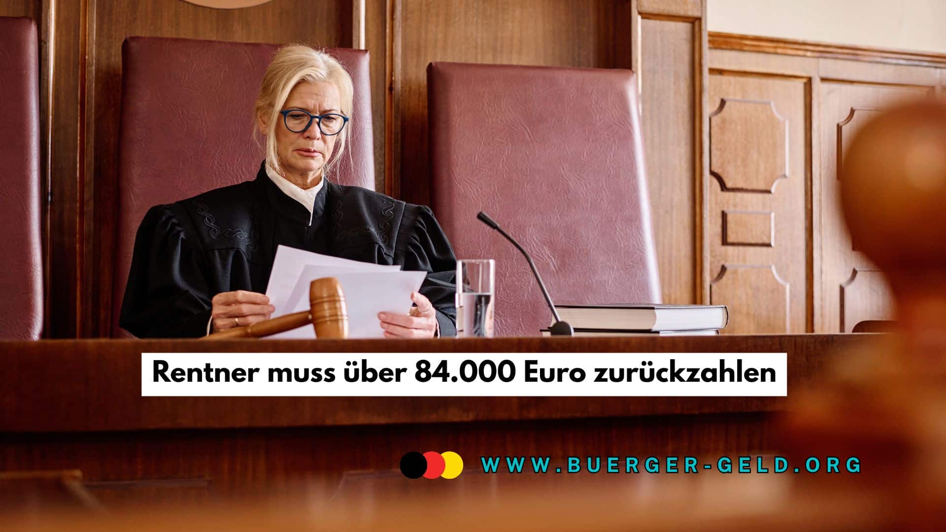 Richterin im Gerichtssaal sitzt an einem großen Holztisch, trägt eine schwarze Robe und liest Gerichtsunterlagen; auf dem Tisch liegen ein Richterhammer, ein Glas Wasser und ein Mikrofon.