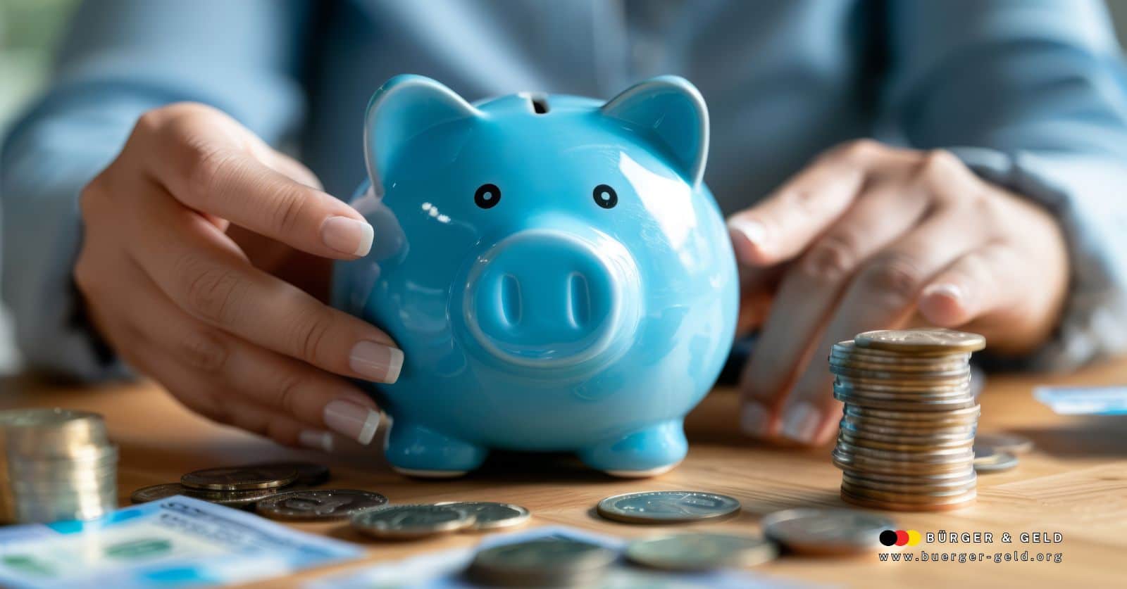 Blaues Sparschwein wird von zwei Händen gehalten, umgeben von Münzen und EC-Karten – symbolisch für private Altersvorsorge und finanziellen Aufbau.