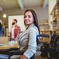 Schwerbehinderung: Integrationshilfen, Förderung und praktische Tipps 4 Arbeitsassistenz unterstützt Frau im Rollstuhl am modernen Arbeitsplatz – Symbol für Integrationshilfen für Menschen mit Behinderung
