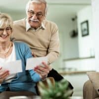 Inflationsausgleich für Rentner: Wird 2025 endlich gerecht entschieden? 4 Älteres Paar sitzt gemeinsam auf dem Sofa und überprüft Rentenbescheide; Symbolbild für die Diskussion um den Inflationsausgleich für Rentner auf Bürger & Geld.