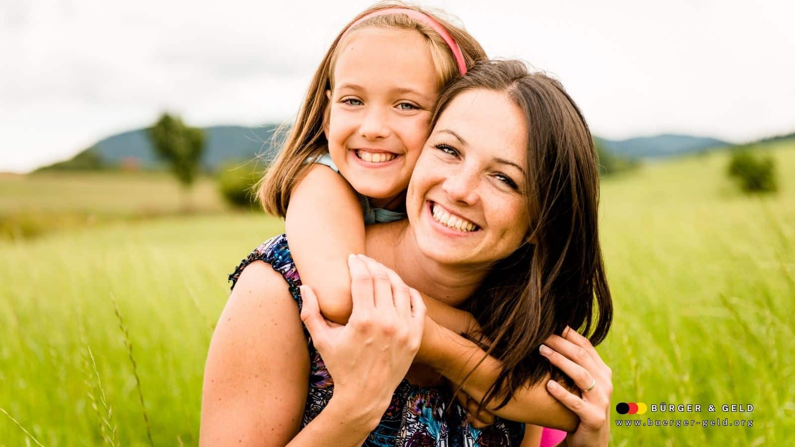 Mutter mit Kind auf dem Arm in einer grünen Wiese – Symbolbild für Eltern, die ihre Kinder selbst erziehen und auf eine Berufstätigkeit verzichten, Fokus auf Rente für Eltern ohne Erwerbstätigkeit.