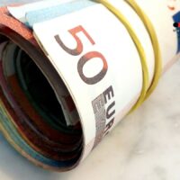 Pflegegeld-Auszahlung im November: Wann das Geld kommt – und warum es für viele Familien überlebenswichtig ist 5 Gerollte Euro-Banknoten mit Gummiband – Symbolbild für Pflegegeld-Auszahlung im November 2025 auf buerger-geld.org