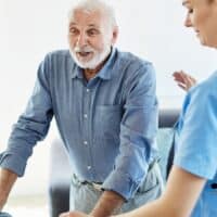 Reform-Schock Pflegeversicherung: Steigende Beiträge, aber auch mehr Leistungen – das erwartet Pflegebedürftige 4 Pflegekraft unterstützt älteren Mann mit Gehhilfe zuhause – Symbolbild für Reformen und Veränderungen in der Pflegeversicherung 2025 in Deutschland