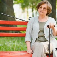 Streit um die Spätehenklausel: Wann Liebe keine Rente bringt 5 Ältere Frau sitzt nachdenklich auf einer Parkbank mit Gehstock – Symbolbild für Streit um Spätehenklausel und Hinterbliebenenrenten.