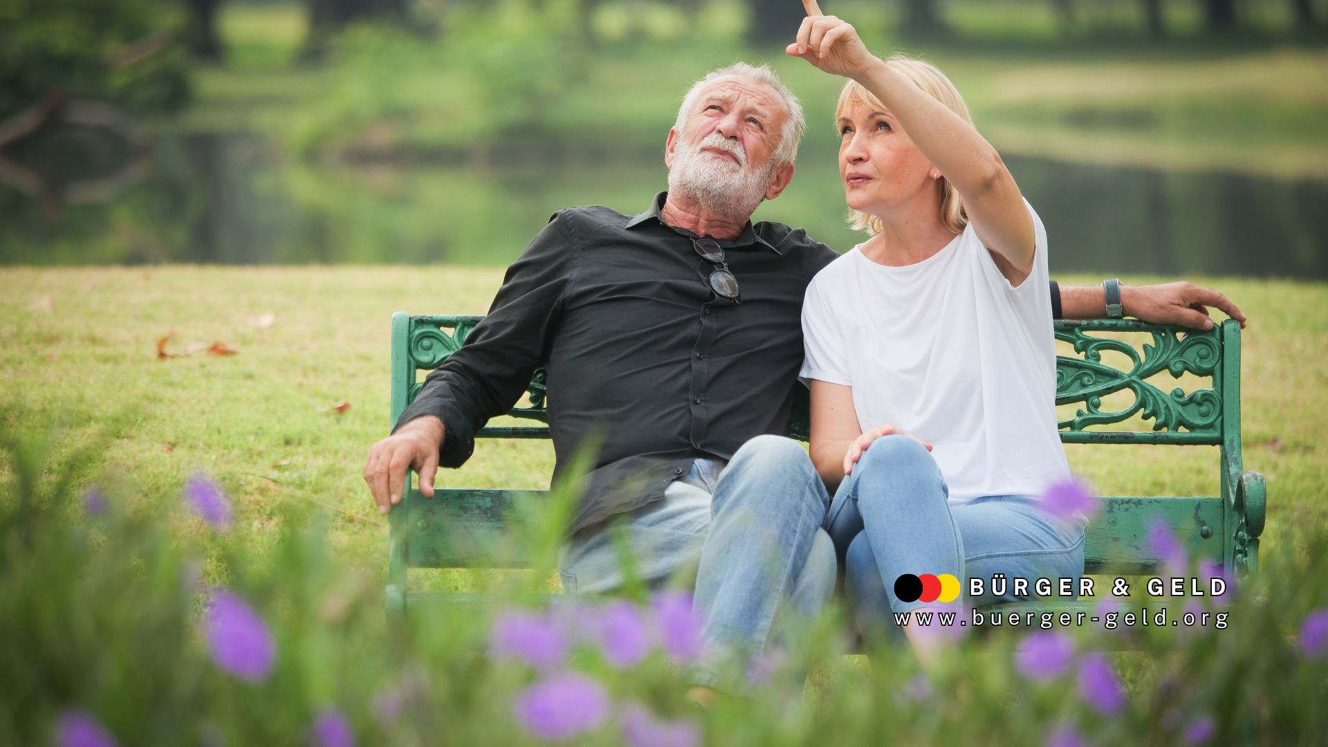 Älteres Paar sitzt entspannt auf einer grünen Parkbank im Freien und genießt den Ruhestand. Die Frau zeigt auf etwas in der Ferne, beide wirken gelöst und glücklich. Im Vordergrund blühen lila Blumen; unten rechts Logo und URL von BÜRGER & GELD sichtbar.