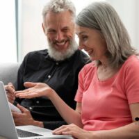 Wer diese 7 Fehler bei Versicherungen macht, zahlt im Alter doppelt 4 Älteres Paar sitzt gemeinsam auf dem Sofa, diskutiert Versicherungsunterlagen am Laptop und wirkt besorgt – Symbolbild für Versicherungsfehler im Alter auf Bürger & Geld.