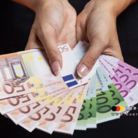 Bürgergeld 2025: 563 Euro Regelsatz, 1.025 Euro Mythos – die ganze Wahrheit 4 Eine Frau hält mehrere Euro-Banknoten als Symbol für Bürgergeld-Auszahlungen – Unterstützung für alleinstehende Sozialleistungsbezieher in Deutschland