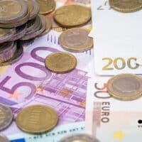 Kindergeld fürs Ausland: Diese Staaten profitieren besonders – gerecht oder Fehlanreiz? 4 Junge Frau mit langen braunen Haaren hält einen Geldschein in beiden Händen; ihr Gesicht ist unkenntlich gemacht. Im Vordergrund steht das Thema Kindergeld; unten rechts ist das Logo des Nachrichtenportals BÜRGER & GELD zu sehen.