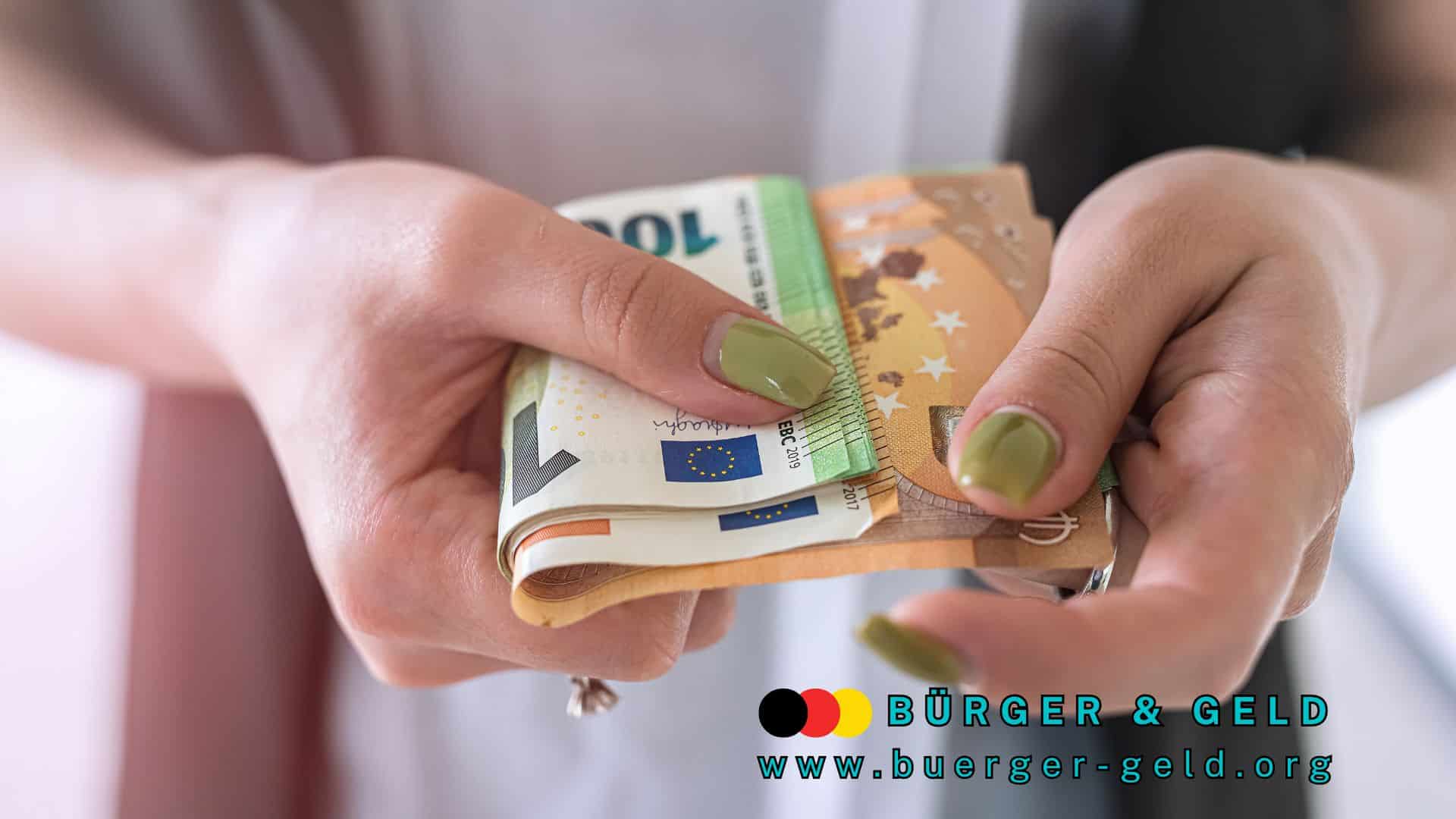 Nahaufnahme von Händen mit grün lackierten Fingernägeln, die mehrere Euro-Geldscheine halten; unten im Bild das Logo und die Webadresse von BÜRGER & GELD (www.buerger-geld.org).