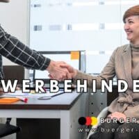 Eine Frau im Rollstuhl sitzt in einem modernen Büro an einem Schreibtisch und reicht einem Mann die Hand zum Handschlag. Auf dem Tisch liegen Büromaterialien wie Stifte und Blätter. Im Bild steht groß das Wort „SCHWERBEHINDERT?“ sowie das Logo von „Bürger & Geld“ und die Website-Adresse.