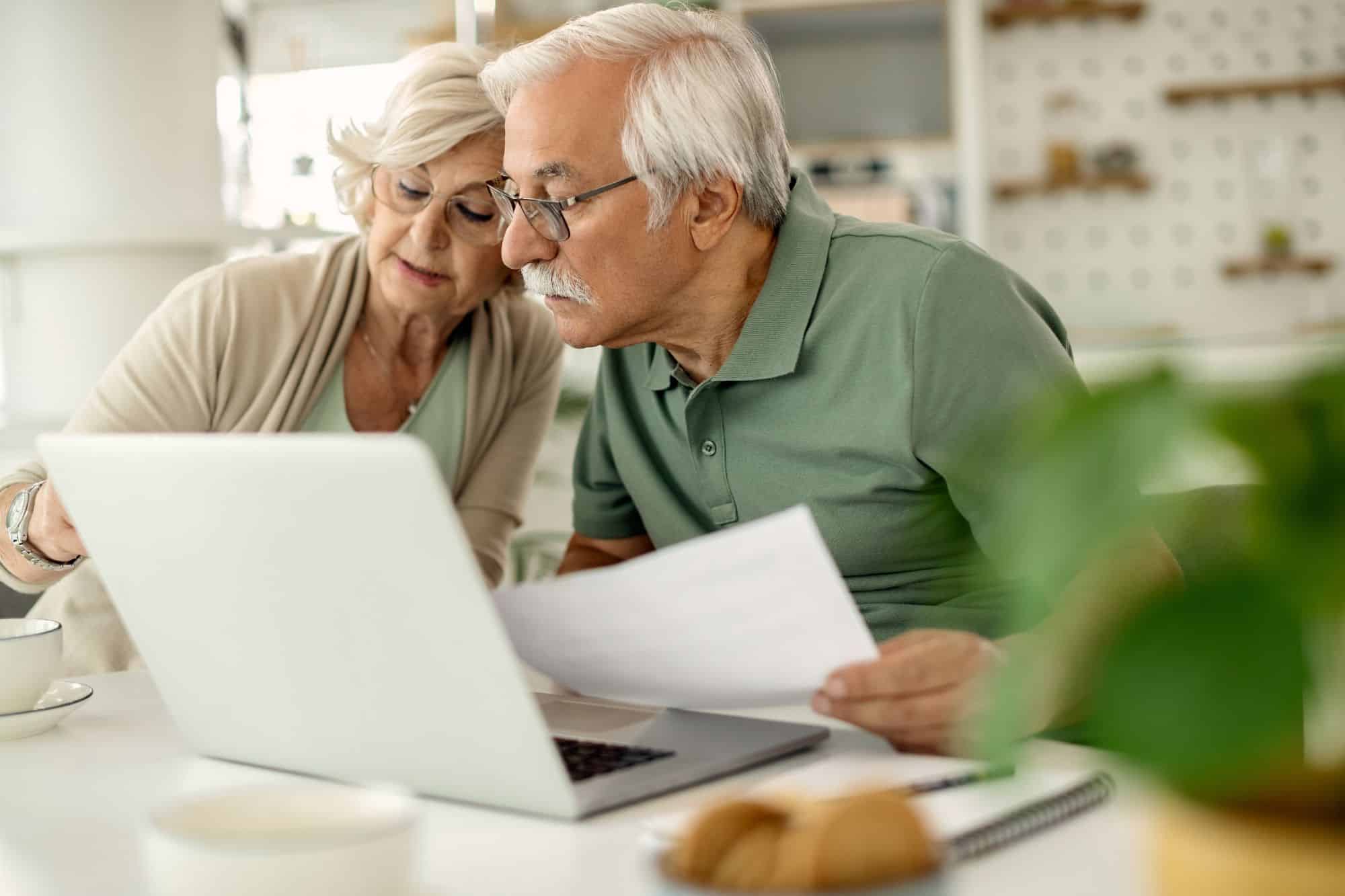 Rentnerpaar sitzt vor ihrem Laptop und macht die Steuererklärung