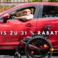 Junger Mann im Rollstuhl steigt auf einem Parkplatz in ein modernes rotes Auto ein. Das Bild symbolisiert Mobilität und Selbstständigkeit von Menschen mit Behinderung.