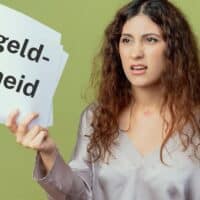 Frau hält ein Schild mit der Aufschrift „Bußgeldbescheid“ vor neutralem Hintergrund als Symbol für Bußgeldverfahren im SGB II beim Jobcenter.