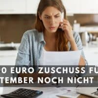 Frau prüft am Küchentisch Dokumente und spricht am Telefon wegen ausstehendem 300-Euro-Mietzuschuss im September; Symbolbild für fehlendes Wohngeld und finanzielle Sorgen.