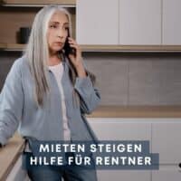 Ältere Frau mit langen grauen Haaren telefoniert in moderner Küche – Thema steigende Mietpreise und Hilfen für Rentner in Deutschland.