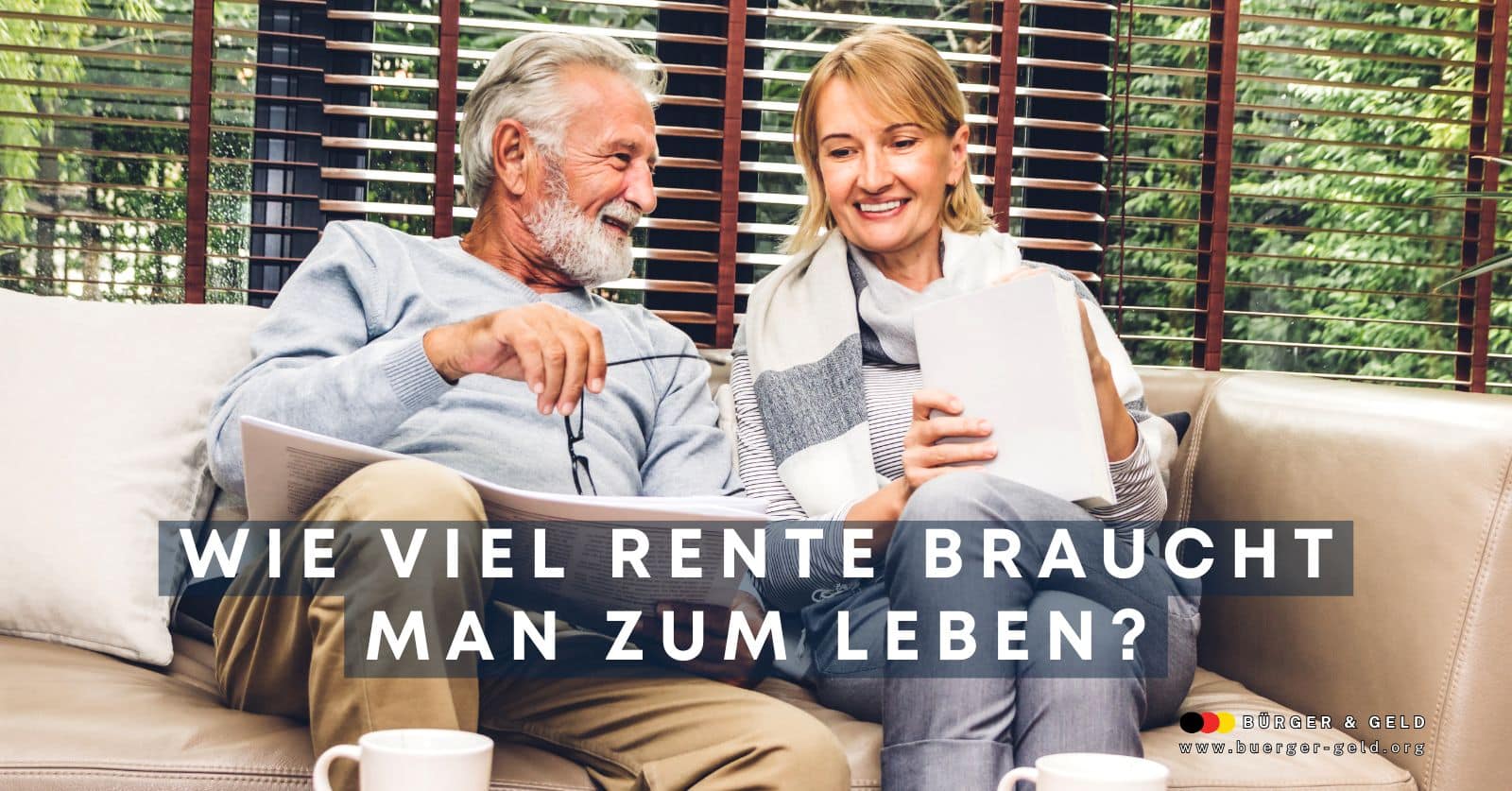 Seniorenpaar sitzt gemeinsam auf dem Sofa und bespricht Rentenunterlagen vor einem großen Fenster – Thema Altersvorsorge und Rentenbedarf.