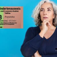 Frau mit grauen Haaren steht nachdenklich vor blauem Hintergrund, links im Bild ist ein Muster eines Schwerbehindertenausweises mit Merkzeichen B zu sehen. Logo von Bürger & Geld unten rechts.