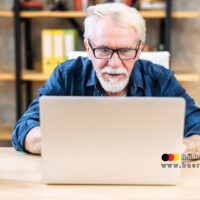 Älterer Mann mit Brille sitzt konzentriert vor einem Laptop und informiert sich online über seinen Steuerbescheid – Symbolbild für die digitale Zustellung von Steuerbescheiden ab 2026 für Rentner in Deutschland.