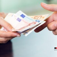 Zwei Hände übergeben sich mehrere Euro-Geldscheine – Auszahlung von Bürgergeld und Arbeitslosengeld im November 2025, Unterstützung für Bedürftige in Deutschland.