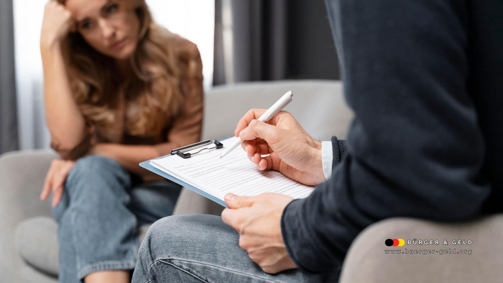 Eine Frau sitzt mit nachdenklicher Haltung auf einem Sessel und spricht mit einer Person, die auf einem Klemmbrett Notizen macht – Beratungsgespräch zur Suchtproblematik im Rahmen des Bürgergelds.