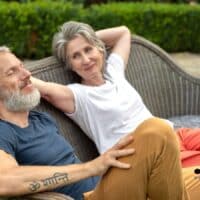 Älteres Paar entspannt lachend auf einer Gartenbank, symbolisch für die neue Rentensicherheit und höhere Renten ab 2027.