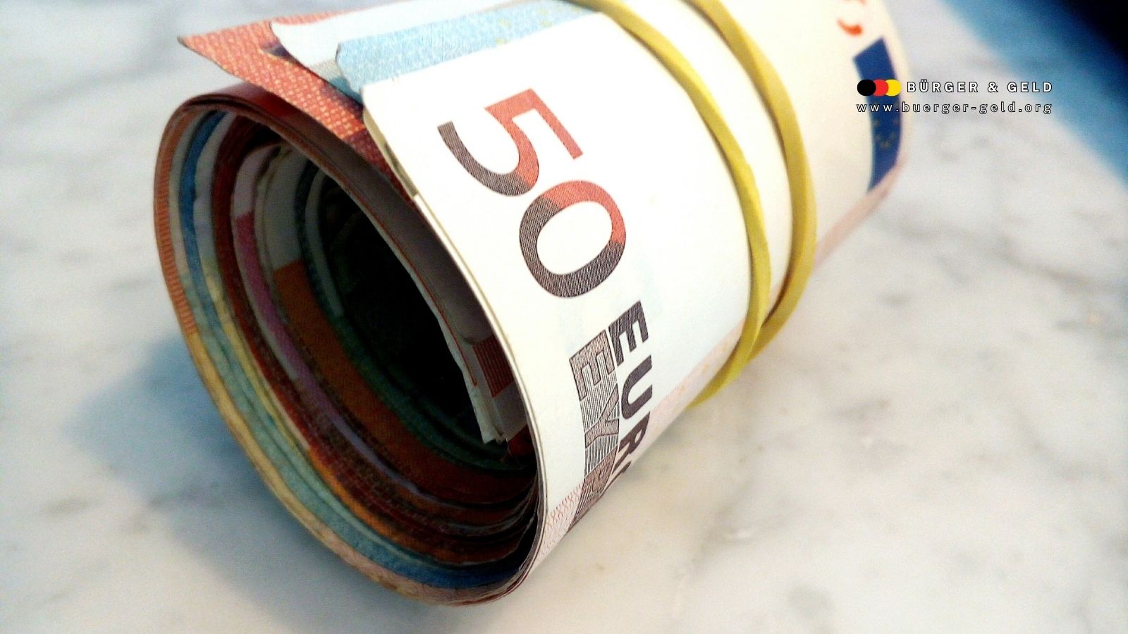 Gerollte Euro-Banknoten mit Gummiband – Symbolbild für Pflegegeld-Auszahlung im November 2025 auf buerger-geld.org