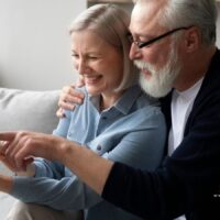 Älteres Paar sitzt zusammen auf dem Sofa und informiert sich mit Tablet über Möglichkeiten, Rentenabschläge in der gesetzlichen Rentenversicherung auszugleichen. Bürger & Geld Magazin.