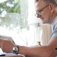 Älterer Mann sitzt nachdenklich am Schreibtisch mit Rentenbescheid und Laptop – Symbolbild für die Unsicherheit und Sorgen bei der Rentenauszahlung im Oktober 2025.