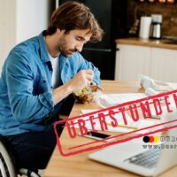 Rollstuhlfahrer arbeitet am Laptop, isst Mittagessen und muss Überstunden leisten – Thema: Schwerbehindertenrechte bei Mehrarbeit, Bürger & Geld Magazin