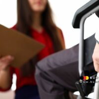 Beratungsgespräch zwischen einer Frau mit Unterlagen und einem Mann im Rollstuhl zur Beantragung des Schwerbehindertenausweises