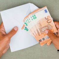 Hände halten einen weißen Umschlag mit mehreren 50-Euro-Banknoten als Symbol für Wohngeld-Auszahlung im November 2025