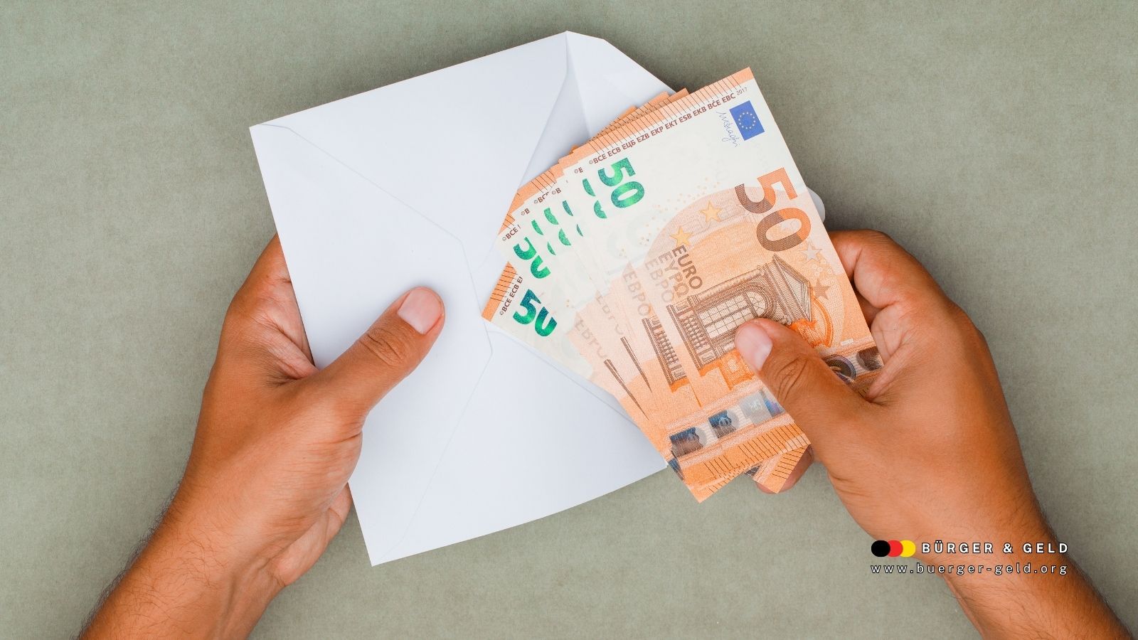 Hände halten einen weißen Umschlag mit mehreren 50-Euro-Banknoten als Symbol für Wohngeld-Auszahlung im November 2025