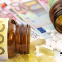 Offene Medikamentenflaschen und Tabletten auf Euro-Geldscheinen symbolisieren steigende Zuzahlungen in der gesetzlichen Krankenversicherung ab 2026